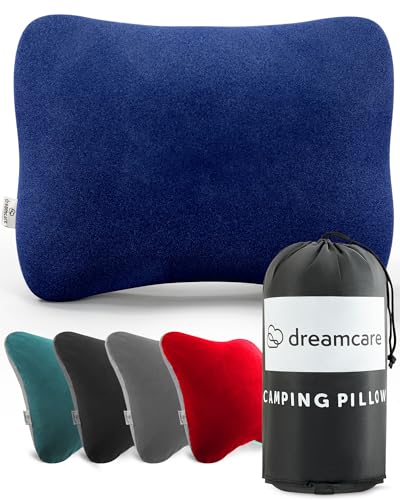 A compact, medium-sized blue camping pillow with an ergonomic hourglass shape and soft microsuede cover, shown rolled up beside its water-resistant travel bag. Ideal for camping, backpacking, and travel.